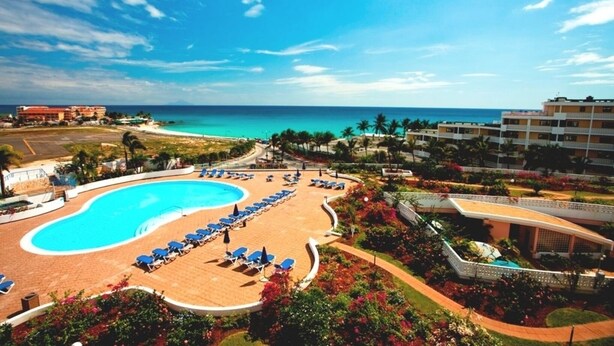 Un resort con una piscina grande, tumbonas y vistas al océano.