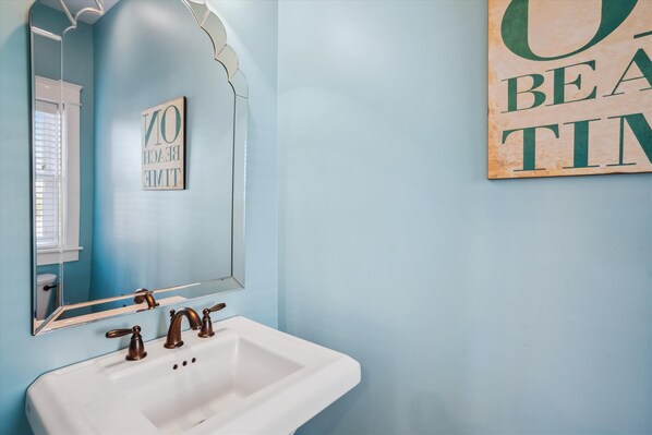A bathroom with a white sink, a mirror, and a wall with a sign that reads "BEAUTY TIME". - 5460- Virginia Dare, 8BR Oceanfront Retreat | Pool, Theater & Game Room (Nags Head)