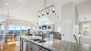A spacious kitchen with a large island, modern appliances, and a view of the ocean. - 5460- Virginia Dare, 8BR Oceanfront Retreat | Pool, Theater & Game Room (Nags Head)