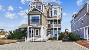 A multi-story building with a prominent bay window and a balcony. - 5460- Virginia Dare, 8BR Oceanfront Retreat | Pool, Theater & Game Room (Nags Head)