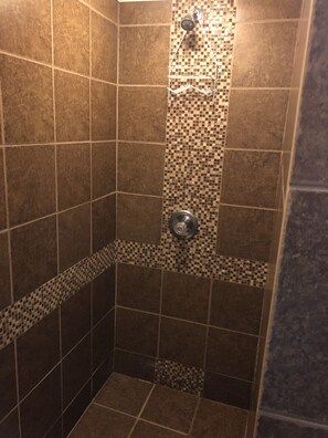 Bañera con ducha, toallas, shampoo, papel higiénico
