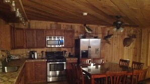 A wooden interior with a kitchen area including a microwave, stove, refrigerator, and wooden cabinets.