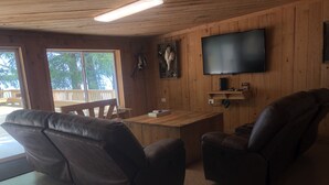 A wooden interior with a leather sofa, a television, and a wooden table.