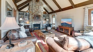A cozy living room with a stone fireplace, leather sofas, and a television.