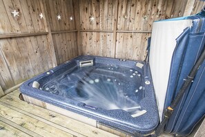 Relax in a hot tub with multiple jets, surrounded by a charming wooden fence with star-shaped decorations.
