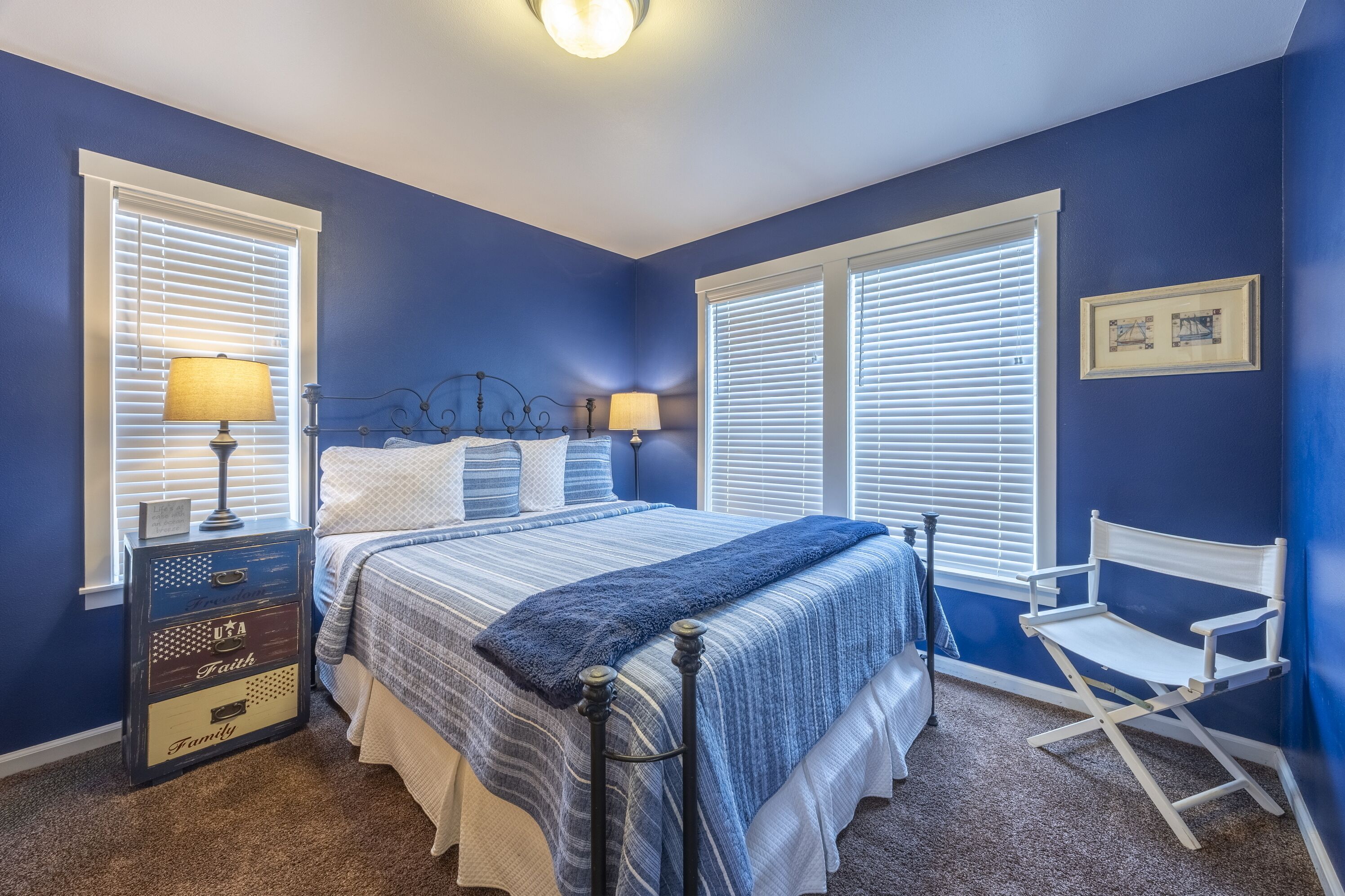 A bedroom with a bed, two bedside lamps, a dresser, and a chair.