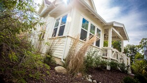 A two-story house with a porch, surrounded by trees and shrubs. - Modern Farmhouse Just Steps From Town and Lake Michigan w/Heated Pool! (New Buffalo)