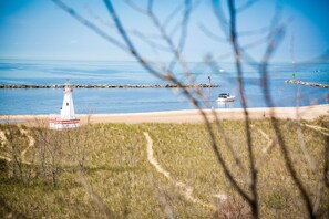 A lighthouse on a rocky outcrop with a clear view of the sea and a sandy beach. - Modern Farmhouse Just Steps From Town and Lake Michigan w/Heated Pool! (New Buffalo)
