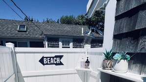 A small, enclosed outdoor area with a wooden deck, a white fence, and a 'BEACH' sign.
