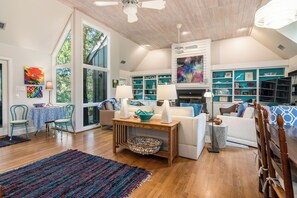 Relax in this inviting living room with a sofa, couch, and coffee table, surrounded by books, decorative items, and a beautiful painting.