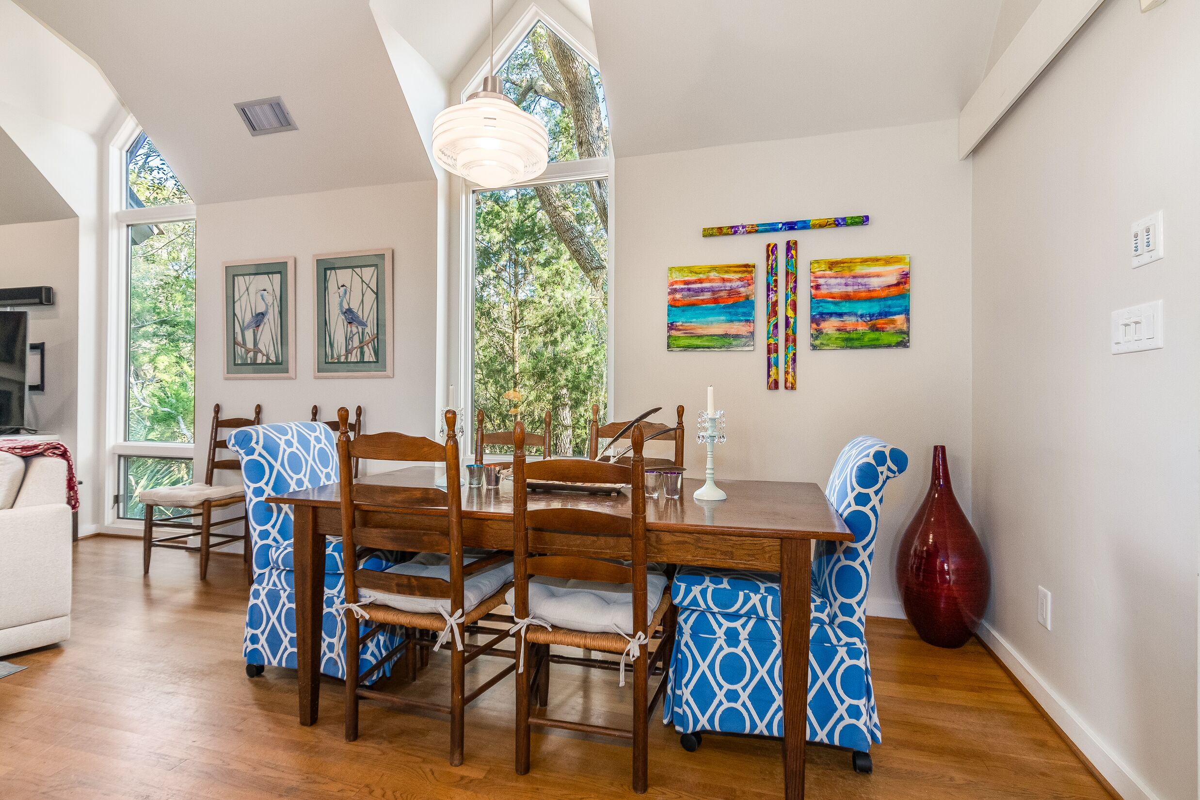 Un coin repas avec une table et des chaises en bois, un vase et des œuvres d’art accrochées aux murs.