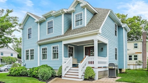 A two-story house with a porch, a staircase, and a grill in the yard. - Experience Cape May charm near Washington St Mall (Cape May)