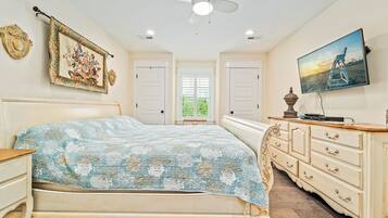 A bedroom with a bed, dresser, and a TV on the wall.