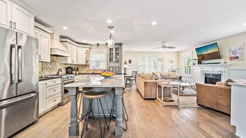 A spacious kitchen with a central island, stainless steel appliances, and a dining area with a sofa and table.