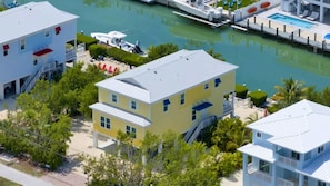 A coastal property with a large house, a dock with boats, and a swimming pool.