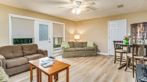 A living room with a sofa, a coffee table, a dining table with chairs, and a ceiling fan. - Near EVERYTHING House-Now Discounted for longer stays (Pensacola)