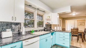 A modern kitchen with white and teal cabinets, a black marble countertop, and a dishwasher. - Near EVERYTHING House-Now Discounted for longer stays (Pensacola)