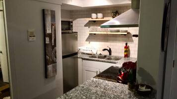 A compact kitchen with a built-in microwave, double sink, and granite countertop.