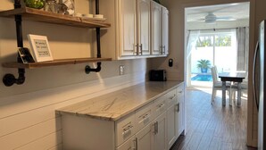 A kitchen with white cabinets, a marble countertop, and a view to the outside. - Anna Maria 2 Family Home w/ pool, beach/3 blocks. (Holmes Beach)