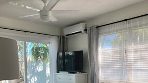 A bedroom with a bed, a TV on a dresser, and a ceiling fan. - Anna Maria 2 Family Home w/ pool, beach/3 blocks. (Holmes Beach)
