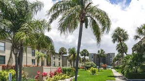 Un quartier résidentiel agrémenté de palmiers, d’une pelouse bien entretenue et d’immeubles modernes dotés de nombreuses fenêtres.