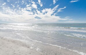 A beach with waves and a clear sky.