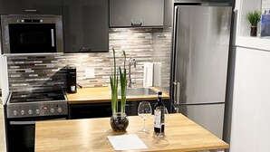 A modern kitchen with a central island, stainless steel appliances, and yellow chairs. - New Basement Private Suite - Fully Furnished,  1 BEDROOM & Futon (Vancouver)