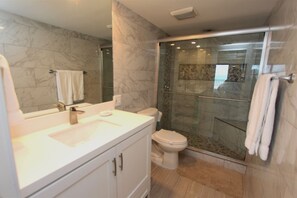 A modern bathroom with a glass-enclosed shower, a white sink, and a toilet. - Experience the ocean views at Dreams of Atlantis - Condo 502, a 2BR retreat in South Padre Island. (South Padre Island)