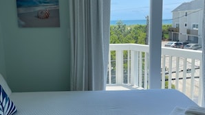 Un dormitorio con una cama grande, vistas al mar y un balcón con barandilla.