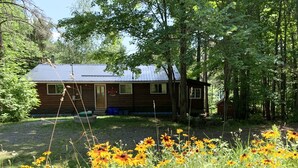 Ein rustikales Blockhaus, umgeben von einem Wald, mit einem Kiesweg, der zur Tür führt.