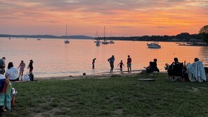 A lakeside scene with people and boats at sunset.