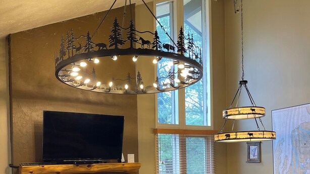A living room with a fireplace, a television, a dining area with chairs, and a chandelier.