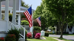 Ein Reihenhaus mit Veranda, zwei amerikanischen Flaggen und gepflegter Bepflanzung.