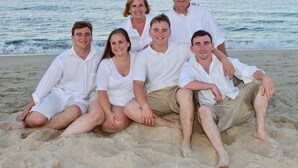 Eine Familie mit sechs Personen am sandigen Strand, das Meer im Hintergrund.