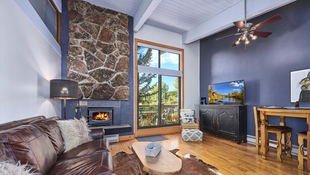 A cozy living room with a stone fireplace, leather sofa, and a wooden coffee table. - ✨ Ski-In/Out Mountain Complex ⎮WIFI + Fireplace + Clubhouse (Steamboat Springs)