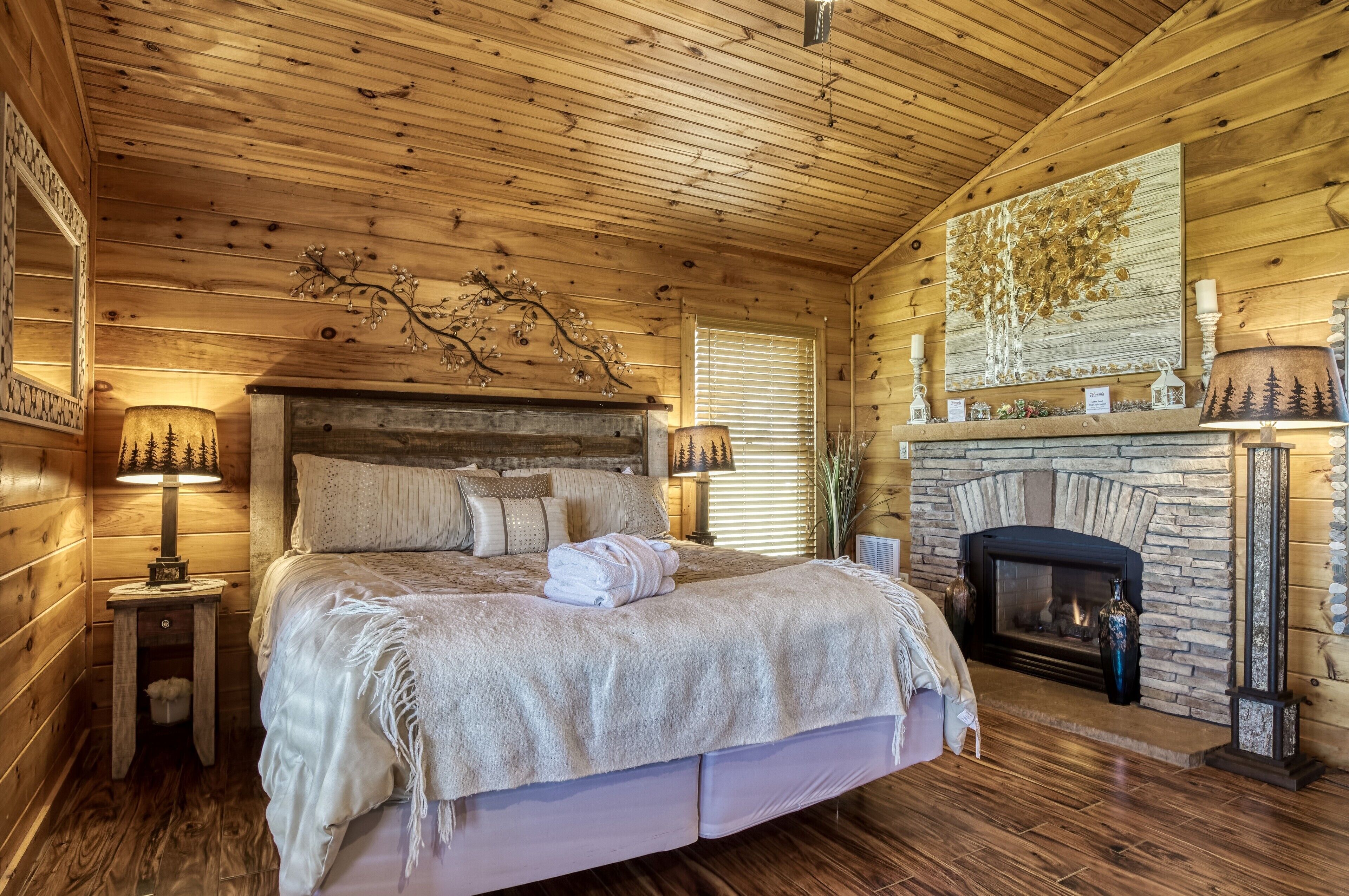 A cozy log cabin bedroom with a large bed, a fireplace, and wooden walls.