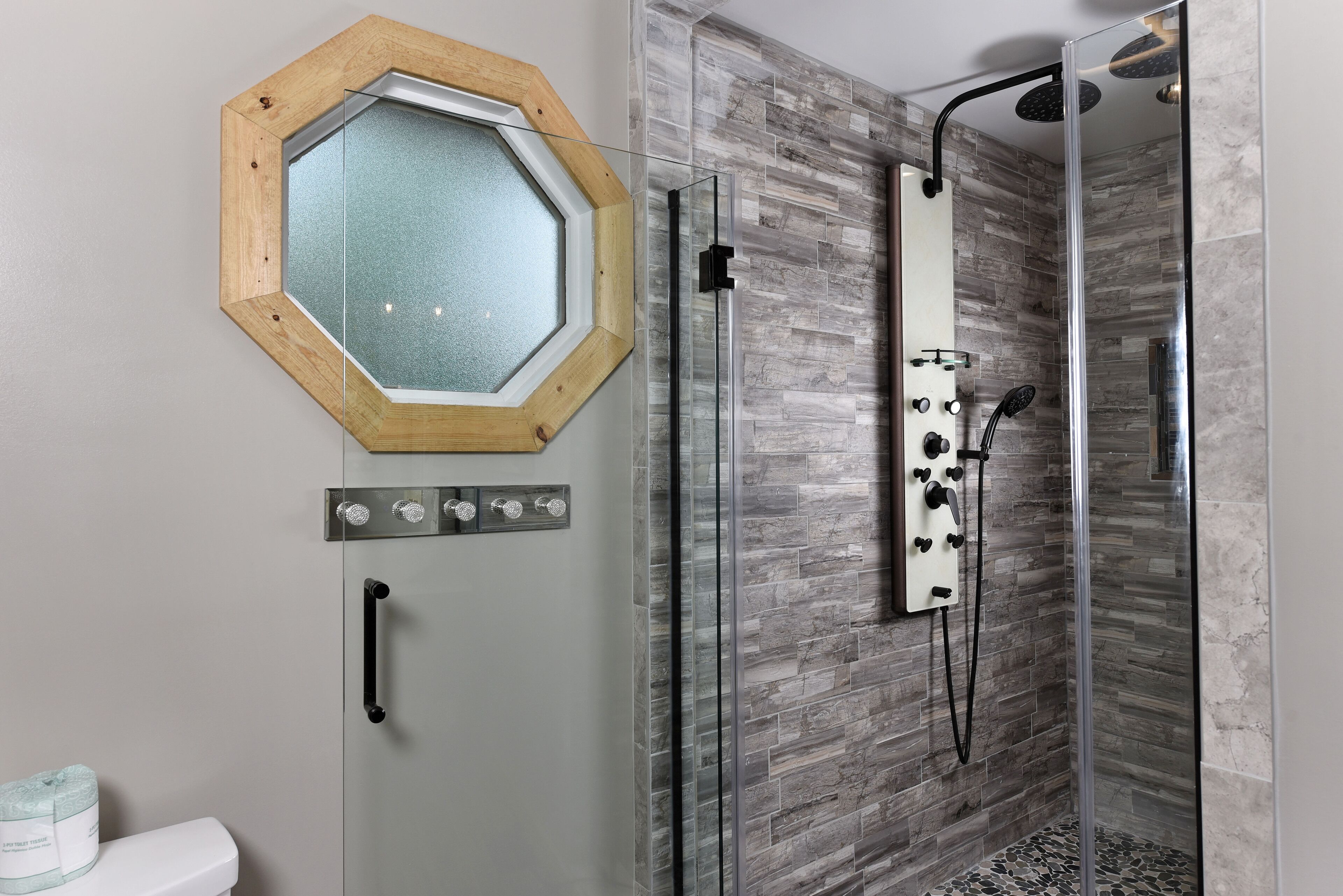 A bathroom with a shower, a toilet, and a mirror.