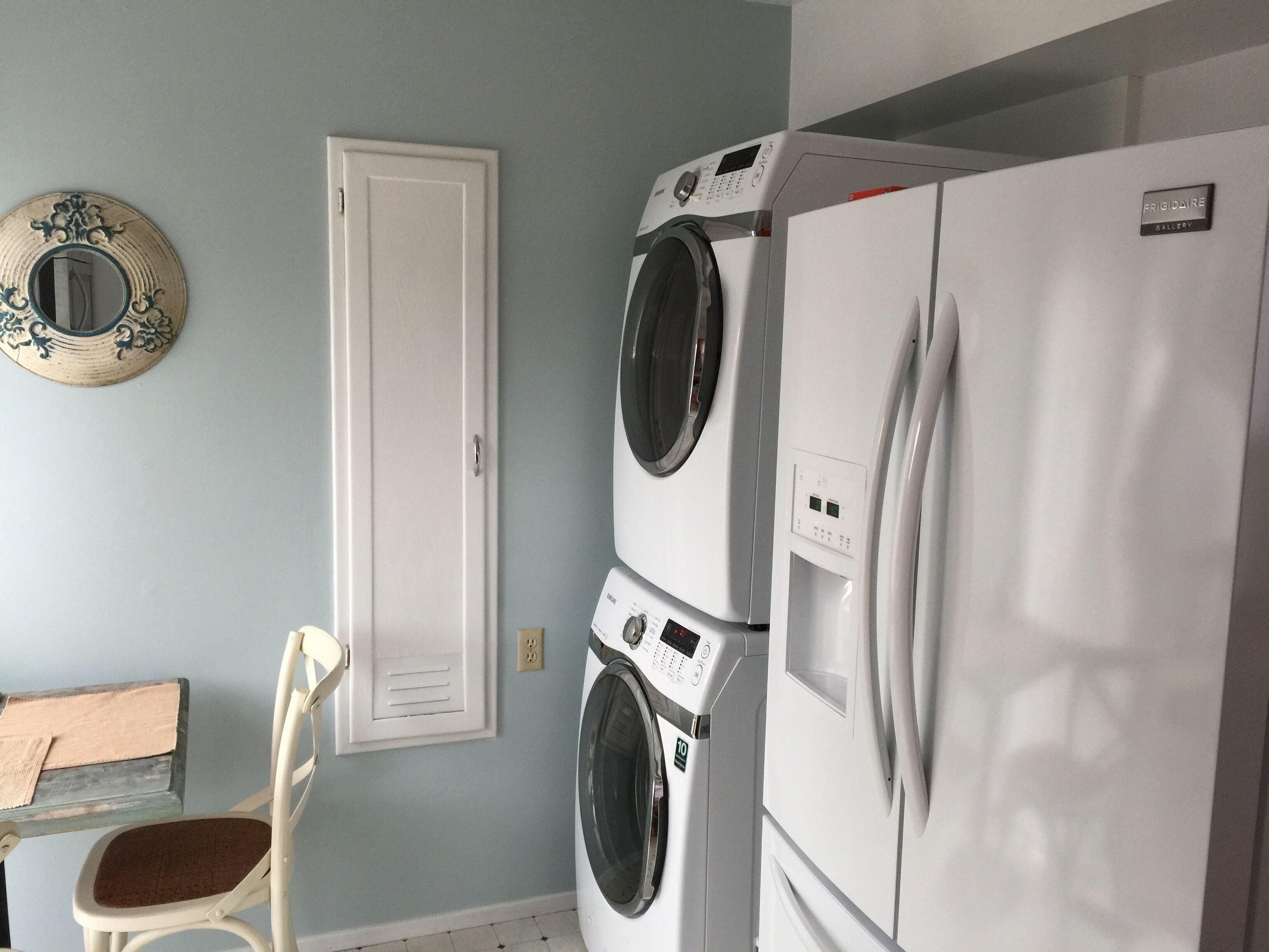 A laundry room with a white door, a washing machine, and a refrigerator.