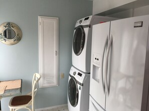 Un cuarto de lavado con puerta blanca, lavadora y refrigerador.