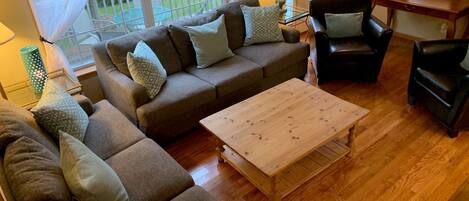 A cozy living room with a brown sofa set, a wooden coffee table, and a black armchair.
