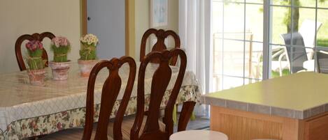 A dining area with a table set for four, surrounded by wooden chairs with cushioned seats.