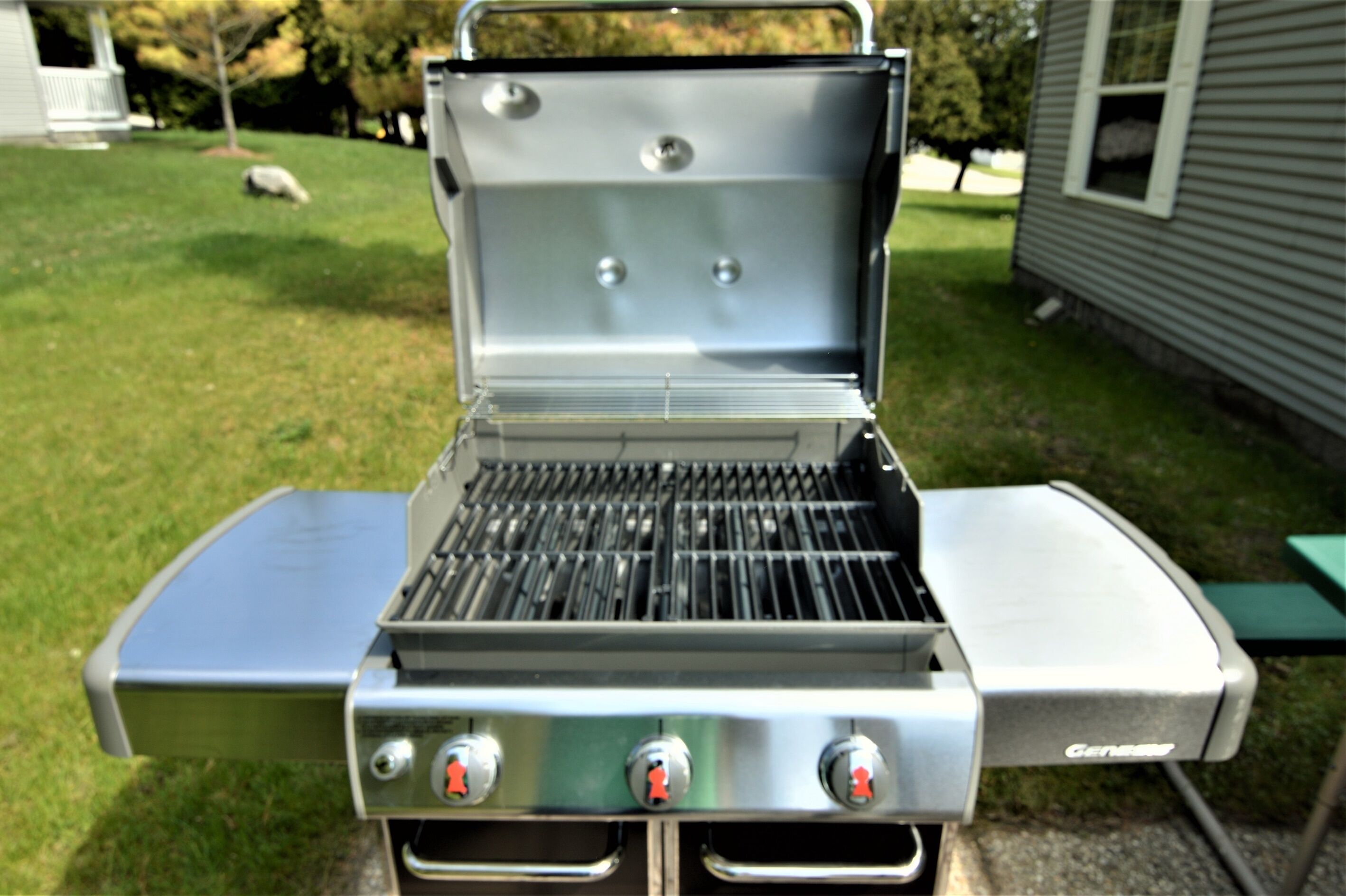Una parrilla Genstar portátil con tapa cerrada, un quemador lateral y un panel de control con tres perillas.