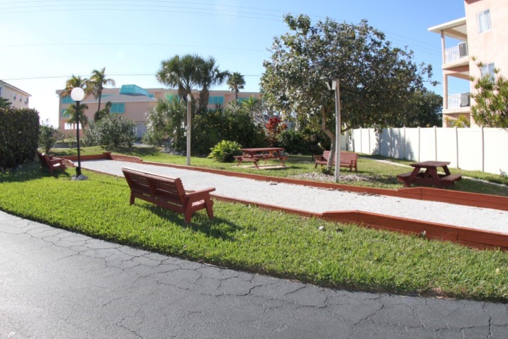 A park with a paved walkway, benches, picnic tables, and a grassy area.