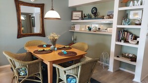 A dining area with a wooden table, wicker chairs, and a hanging light fixture. - 10/10 EXCEPTIONAL!!! -161 REVIEWS-ANNA MARIA ISLAND-2B/2B-RENOVATED-WELL STOCKED (Bradenton Beach)