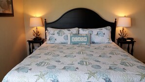 A bed with a quilted headboard, two bedside tables with lamps, and decorative pillows. - 10/10 EXCEPTIONAL!!! -161 REVIEWS-ANNA MARIA ISLAND-2B/2B-RENOVATED-WELL STOCKED (Bradenton Beach)