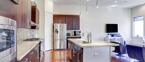 A modern kitchen with stainless steel appliances, wooden cabinets, and a central island.