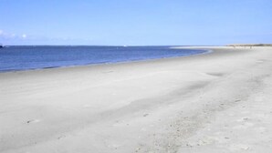 Une vaste plage de sable fin, avec une mer calme et un ciel dégagé.