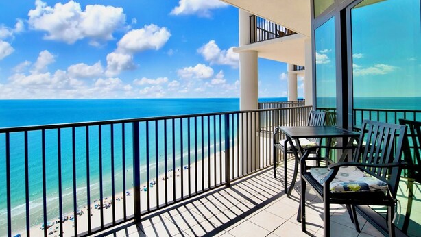 A balcony with a view of the ocean and beach, featuring a table and chairs. - The Oasis 2010 | Spacious, Lazy River, Poolside Grill, New Splash Pad, Pool with Slide! (Orange Beach)