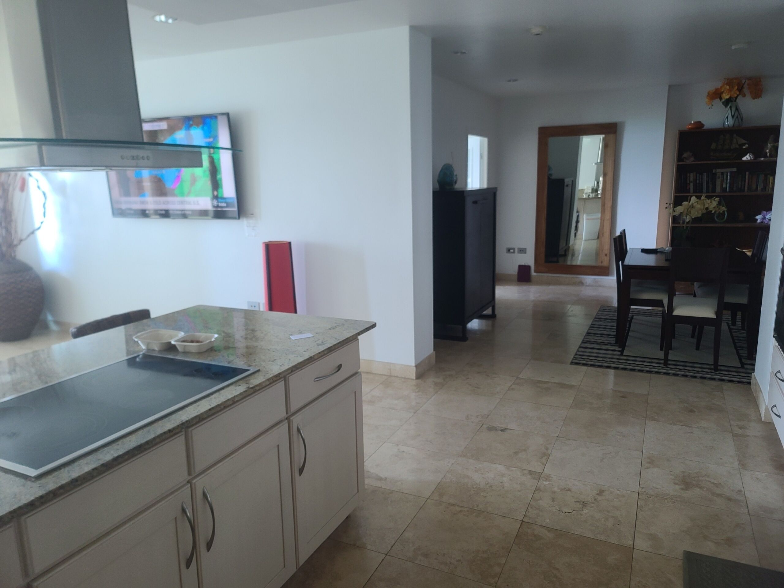 A modern kitchen with a granite countertop, stainless steel appliances, and a dining area with a wooden table and chairs.