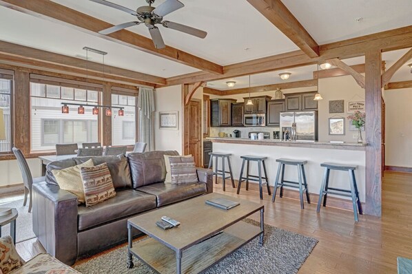 A spacious living area with a leather sofa, a coffee table, and a bar area with stools. - Chalakee Lodge CH4- Mountain View, Gated Resort, Indoor/Outdoor Pools & Hot Tubs (Boone)
